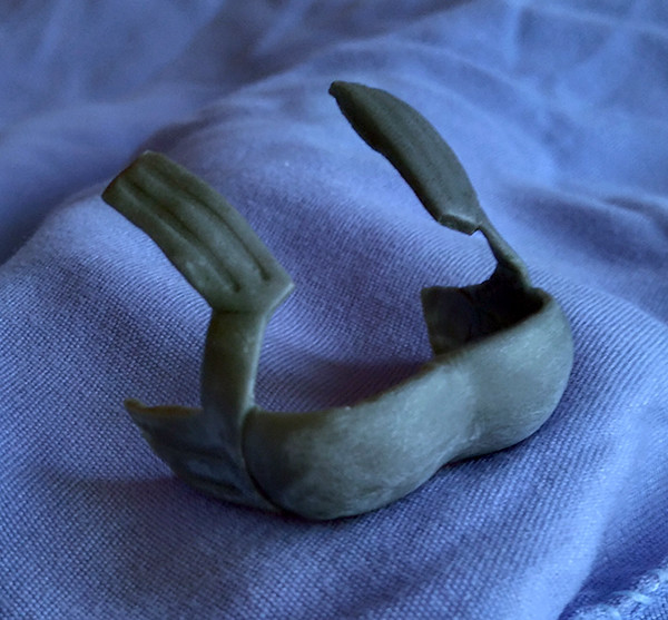 Hard copy made with Apoxie Sculpt.

Press it into a blob of Sculpey to make a simple mold, and bake it.

Brush layers of liquid latex into the mold until it's the thickness you want. Takes forever, but you get some nice detailed flexible armor pieces.