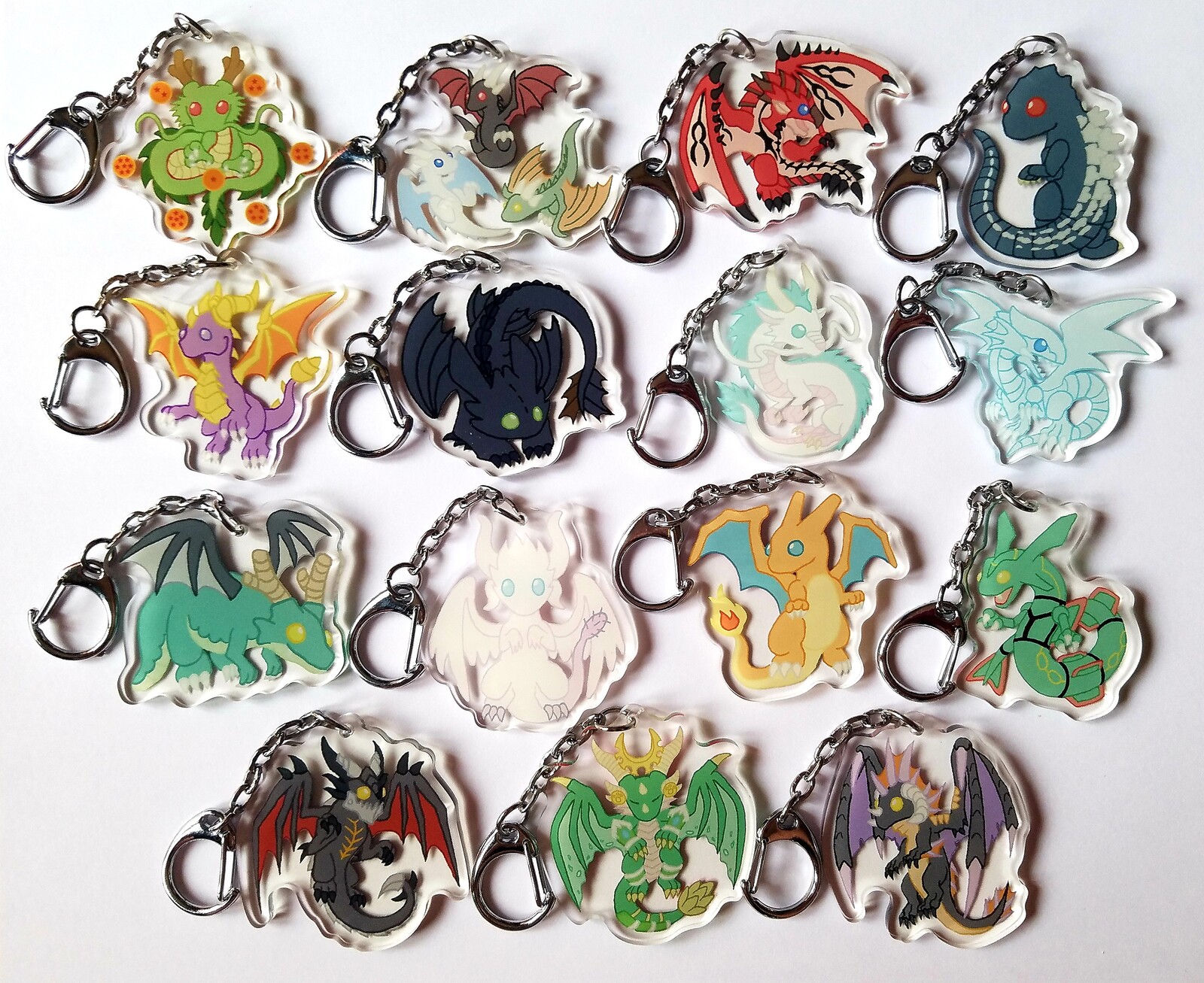 Acrylic charms of a variety of dragons from different series. Shenron, Game of Thrones, Rathalos, Godzilla, Spyro, Toothless, Haku, Blue Eyes White Dragon, Tohru, Kanna, Charizard, Rayquaza, Deathwing, Ysera, and Onyxia. 128 total designs available. 