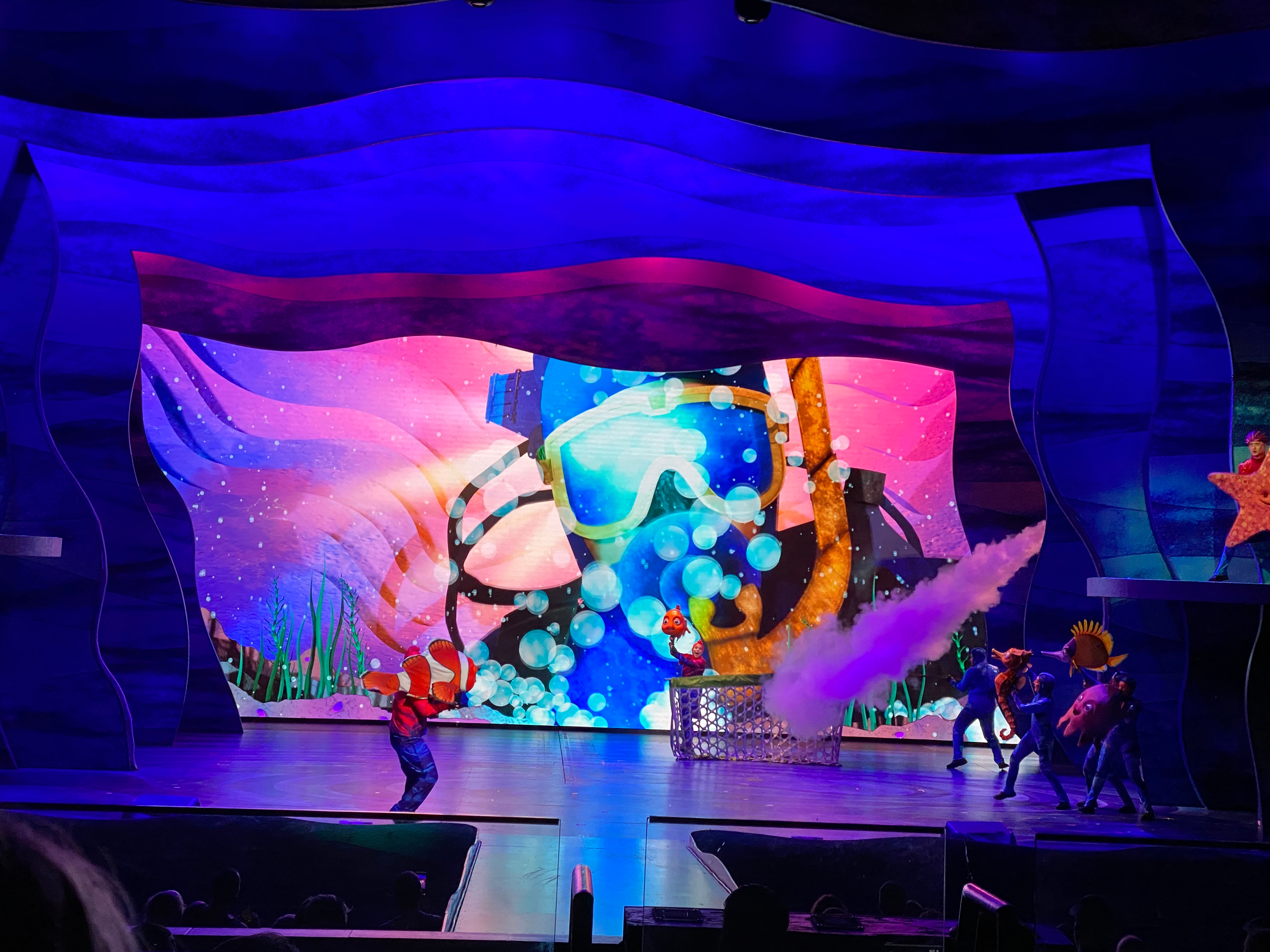 The diver appears on stage in a rush of bubbles, surprising the performers