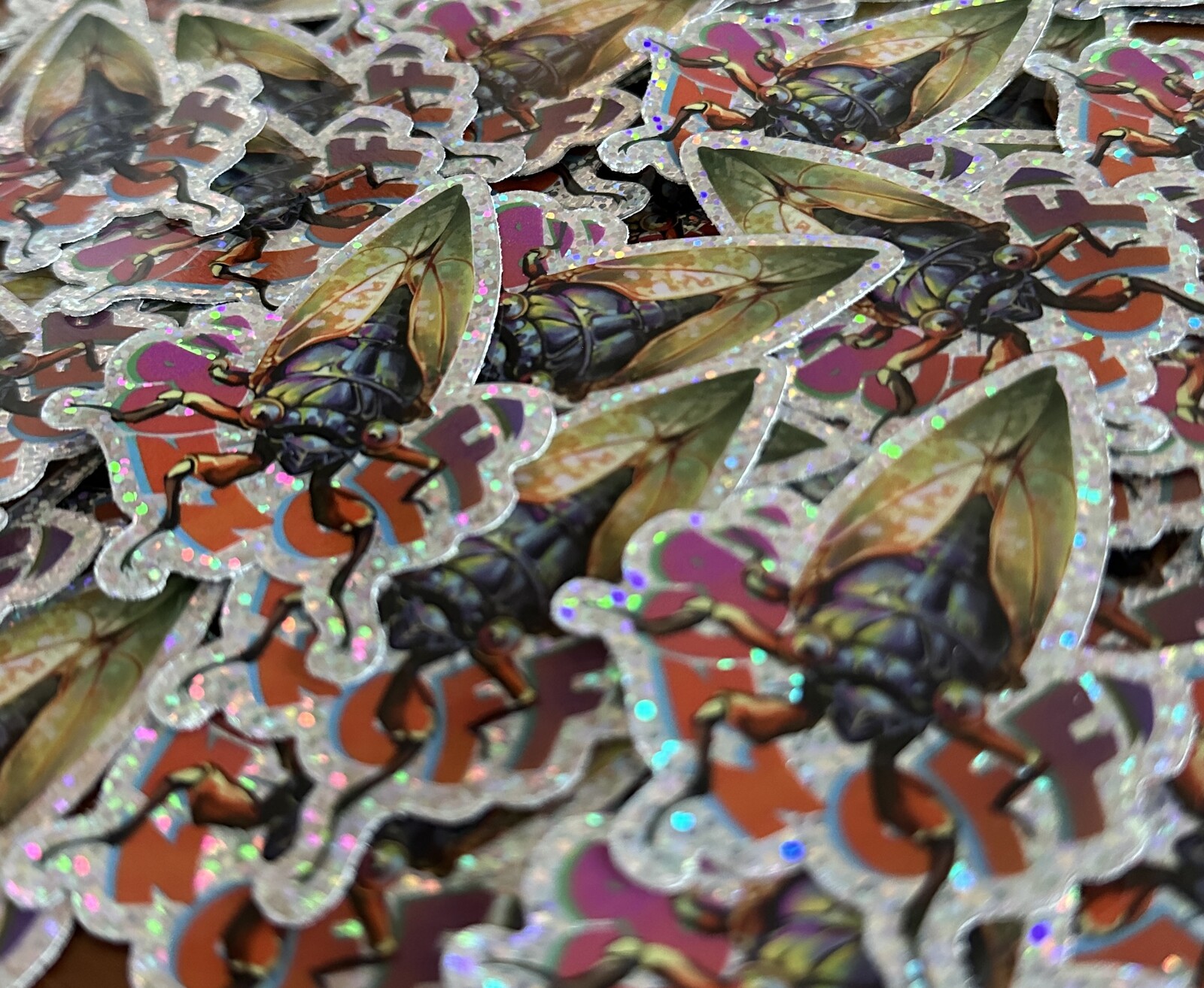 Zoomed in view of a gathering of glittery "Buzz Off" stickers.