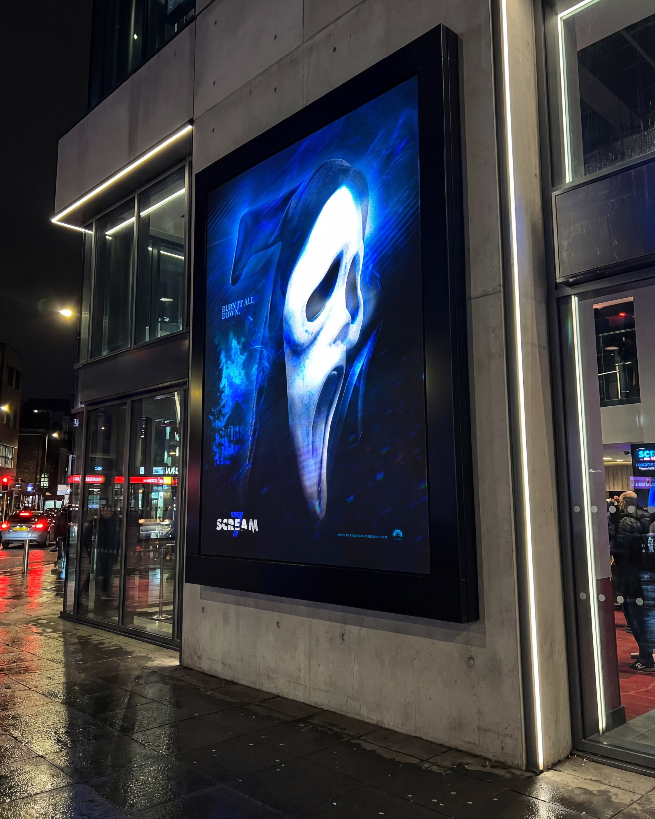 A closer, ground-level placement emphasizing scale and presence. The mask becomes confrontational, forcing direct engagement with passersby